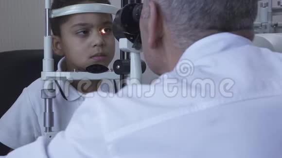 小帅哥在诊所做眼科检查坐在医生面前穿着白色的医用外套看着验眼机视频的预览图