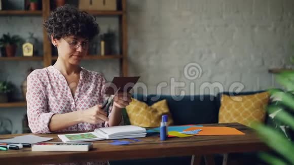 有创意的年轻女人正在用剪刀剪一张纸然后把它放进笔记本检查一下视频的预览图