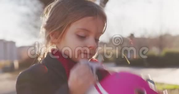 幸福女儿小女孩在城市公园骑自行车前戴上安全帽童年积极的安全概念视频的预览图