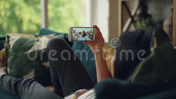 年轻女性上网与朋友交谈时看着屏幕坐在沙发上说话视频的预览图