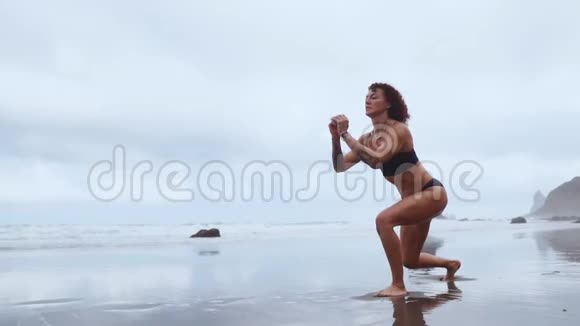 一位身材苗条的女士在海洋附近散步在水上运动在每条腿上表演弓步大腿肌肉锻炼视频的预览图