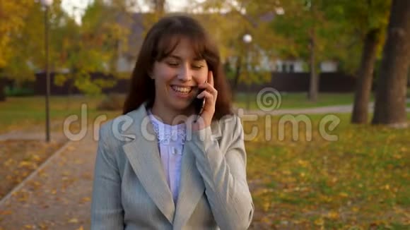 年轻漂亮的女人在公园里用手机说话快乐的女孩微笑视频的预览图