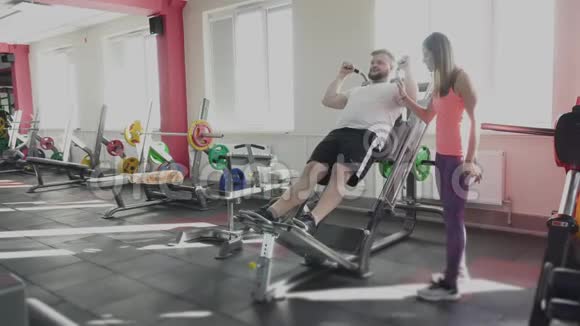 他和私人教练在健身房的训练模拟器上摆动腿部肌肉个人减肥训练视频的预览图