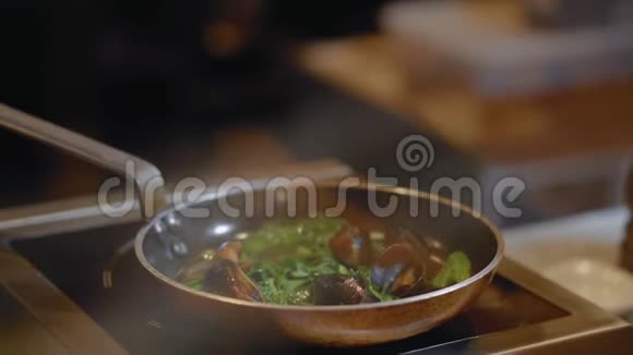 在油和大蒜的煎锅上近距离观察用叶子煎煮的贻贝餐厅厨房准备海鲜视频的预览图