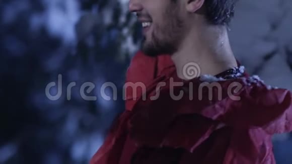 穿着红色衣服的年轻人在白雪皑皑的冬林中微笑着慢慢地移动视频的预览图