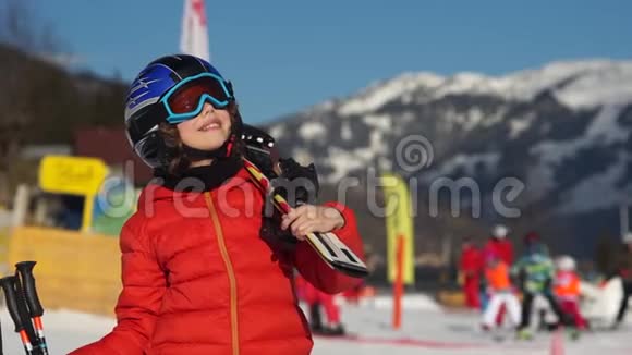 一个滑雪场的男孩一个穿着全套滑雪装备的孩子穿着红色夹克戴着眼镜和头盔看着天空这就是视频的预览图