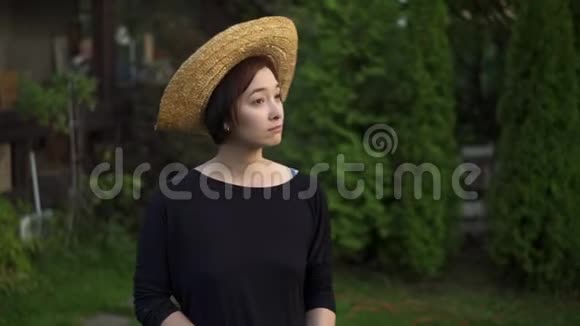 戴着草帽微笑的亚洲女人用水管浇树视频的预览图