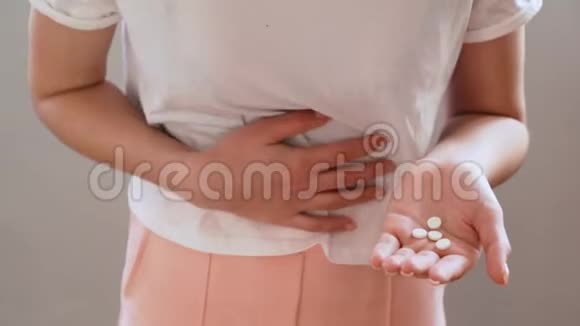 腹部疼痛的年轻女子手中的药丸特写视频的预览图