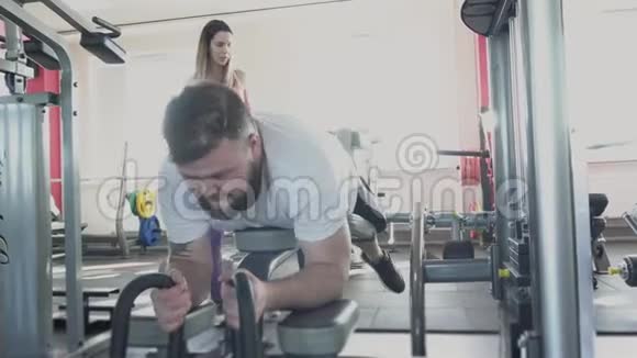 他和私人教练在健身房的训练模拟器上摆动腿部肌肉私人减肥演习视频的预览图