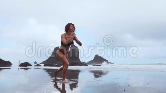 在海洋中女性练习者在岩石和水的背景下交替着每一条腿培训视频的预览图
