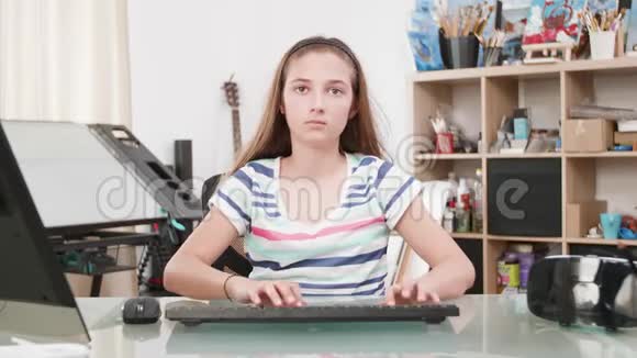 一个十几岁的女孩在电脑上打字的肖像视频的预览图