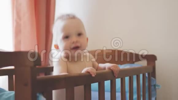 小有趣的男孩站在婴儿床上笑微笑可爱的孩子站在操场上快乐的童年概念视频的预览图