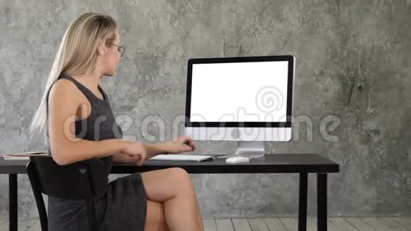 开朗的年轻女人坐在办公室里和相机交谈在电脑上展示一些东西白色显示器视频的预览图