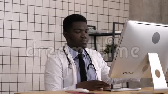 年轻的非裔美国医生在他的电脑上做笔记和查找一些东西视频的预览图