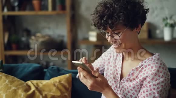 快乐女孩用智能手机看屏幕笑着发短信给朋友并在网上查看社交媒体账户视频的预览图