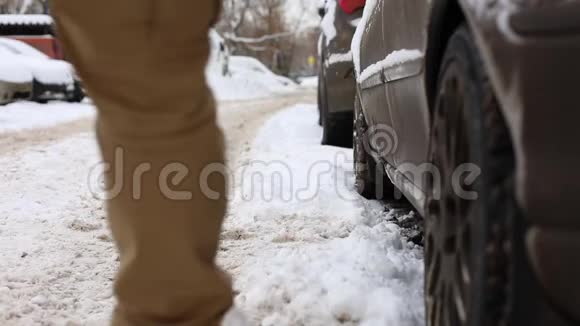 男人在坐在车里开车走之前先把雪从腿上抖下来视频的预览图