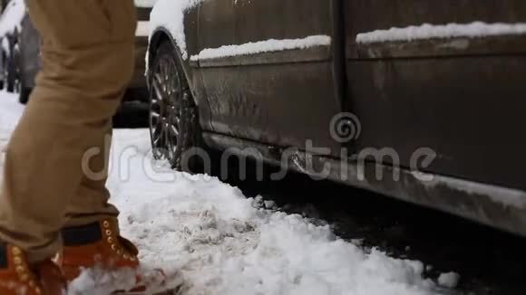 男人在坐在车里开车走之前先把雪从腿上抖下来视频的预览图