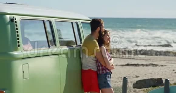一对年轻夫妇在阳光明媚的4k天气拥抱在面包车附近视频的预览图