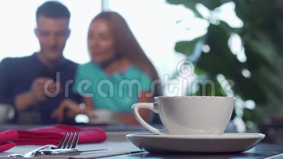 有选择地把注意力集中在桌子上的一个杯子上两个人在背景上拥抱视频的预览图