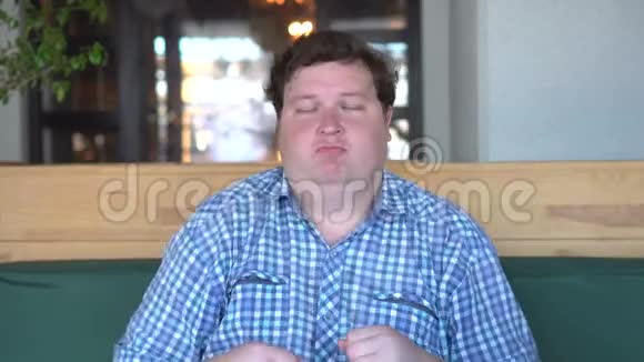 英俊的年轻胖子穿着衬衫在咖啡馆或餐馆跳舞坐着跳舞的胖子视频的预览图