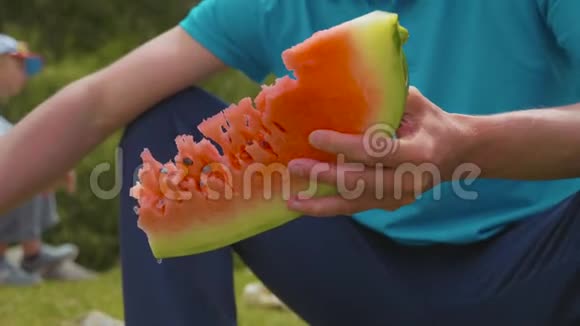 男人在户外吃新鲜的甜西瓜近距离拍摄视频的预览图