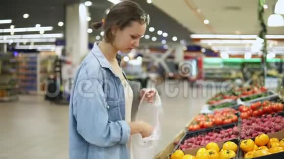 购物女人在蔬菜商店或超市选择生物食品黄色番茄一个接一个地把它放进视频的预览图