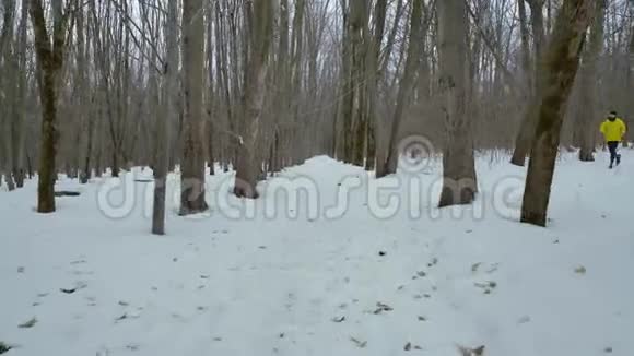 运动健美男子在森林中奔跑在白雪覆盖的道路上过冬视频的预览图