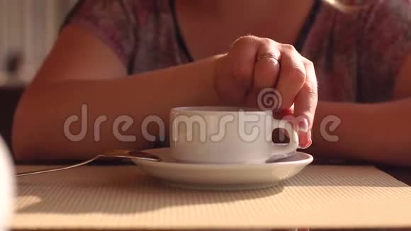 女孩在咖啡馆里喝着小白杯茶特写慢动作视频的预览图