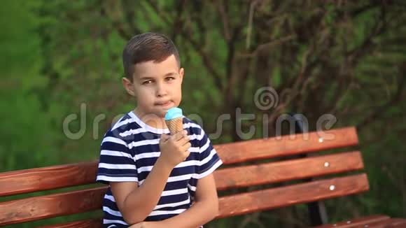 一个穿条纹T恤的小男孩正在吃蓝色冰淇淋春天晴朗的天气视频的预览图