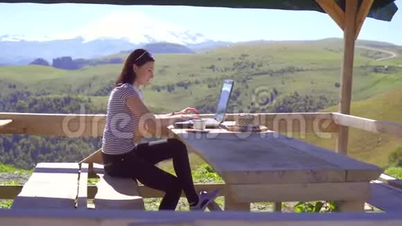 女自由职业者在山区的笔记本电脑上远程工作视频的预览图