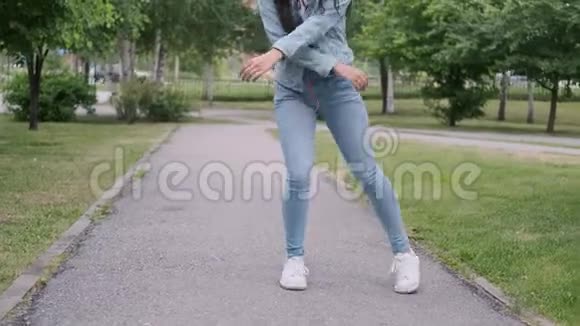 有趣的快乐女孩在公园里跳舞听着耳机上的音乐视频的预览图