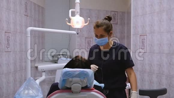 年轻的女牙医治疗病人牙齿在口腔医生那里接受治疗视频的预览图