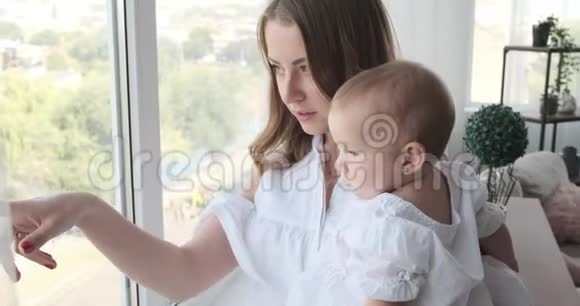妈妈带着小女孩从窗户往外看视频的预览图