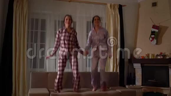 两对幸福的双胞胎姐妹在帕詹姆斯在一个舒适的客厅里在沙发上跳跃像在童年一样玩得很开心视频的预览图