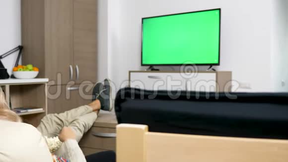 幸福的一对夫妇在他们舒适的公寓里看着绿色屏幕的大屏幕电视视频的预览图