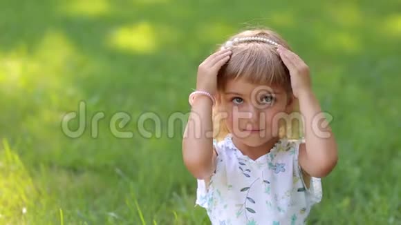 小女孩的特写多种颜色的眼睛坐在夏日公园的草地上视频的预览图