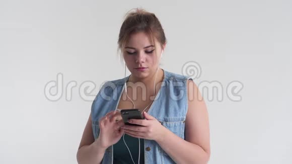 胖女人用手机耳机听音乐视频的预览图