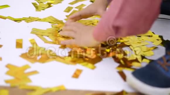 特写孩子们手在玩着金光闪闪的东西从饼干里冒出的金色的火花节日的金属装饰品视频的预览图