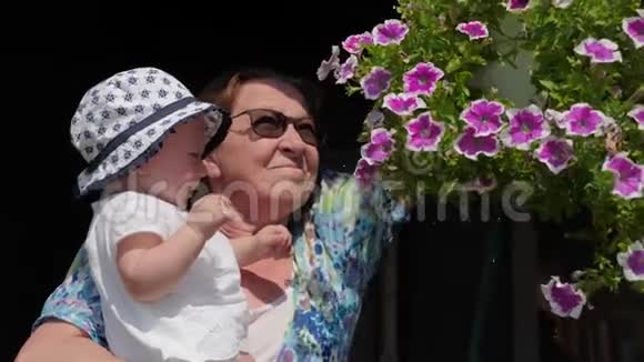 装饰用的花娇艳的花朵祖母带着婴儿浇花视频的预览图