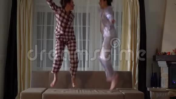 两个快乐的姐妹一对双胞胎在一个舒适的客厅里跳在沙发上像童年一样玩得很开心视频的预览图