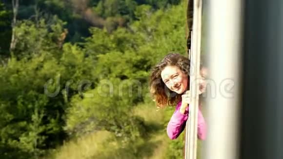 女游客从火车窗口探出身子乘火车旅行自由和冒险的概念视频的预览图