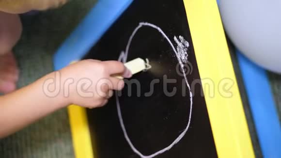 特写幼儿手拿粉笔在手画一幅黑板画画在黑板上视频的预览图