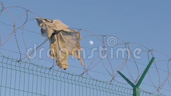 为使移民远离而竖起的铁丝网上挂着一件破烂的衬衫带刺铁丝网的高障碍物视频的预览图