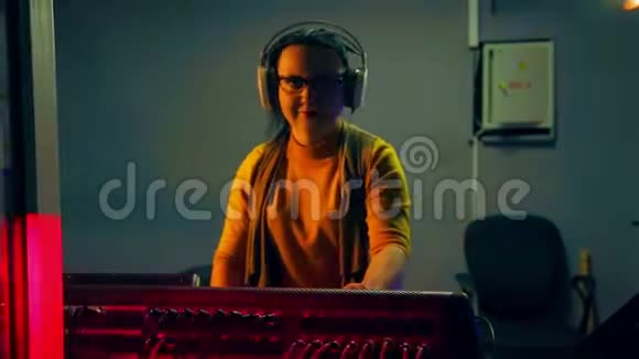 一位带耳机的女DJ在一个技术室的灯光下在一个混合控制台进行迪斯科视频的预览图