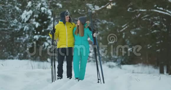 在冬季森林滑雪行走期间一个有爱心的年轻人帮助受伤的女友的完整画像视频的预览图