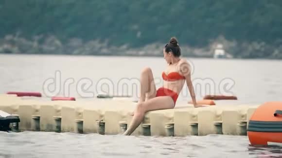 穿着红色比基尼的美女坐在海上的浮桥上视频的预览图