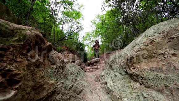 自然森林中背着背包奔跑跳跃的男子旅行者的慢动作视频的预览图