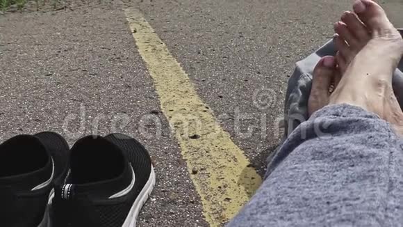 女子赤足背着背包坐在柏油路上一辆辆黄色的单行道等待车视频的预览图