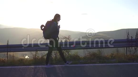 女孩带着背包旅行在他身后的路上慢悠悠视频的预览图