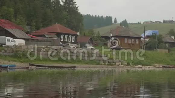 古老的俄罗斯村庄有古老的木屋乡村道路和小河岸上绿油油的青草视频的预览图